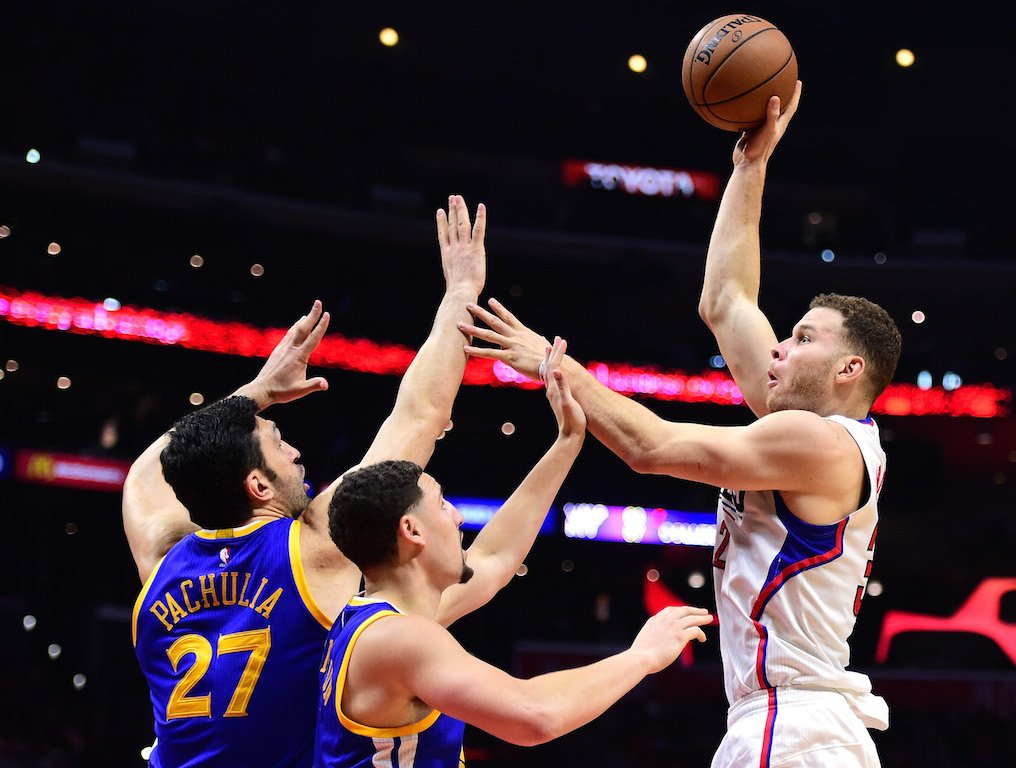 Blake Griffin (R) soars past the Warriors to score.