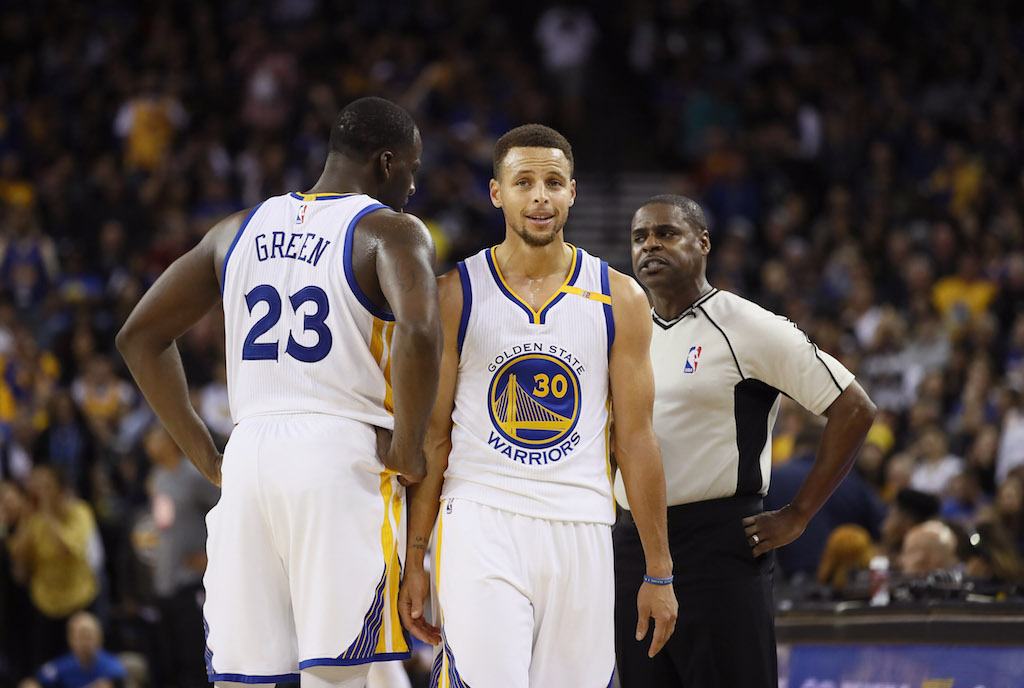 Draymond Green and Stephen Curry talk as they pass each other on the court.