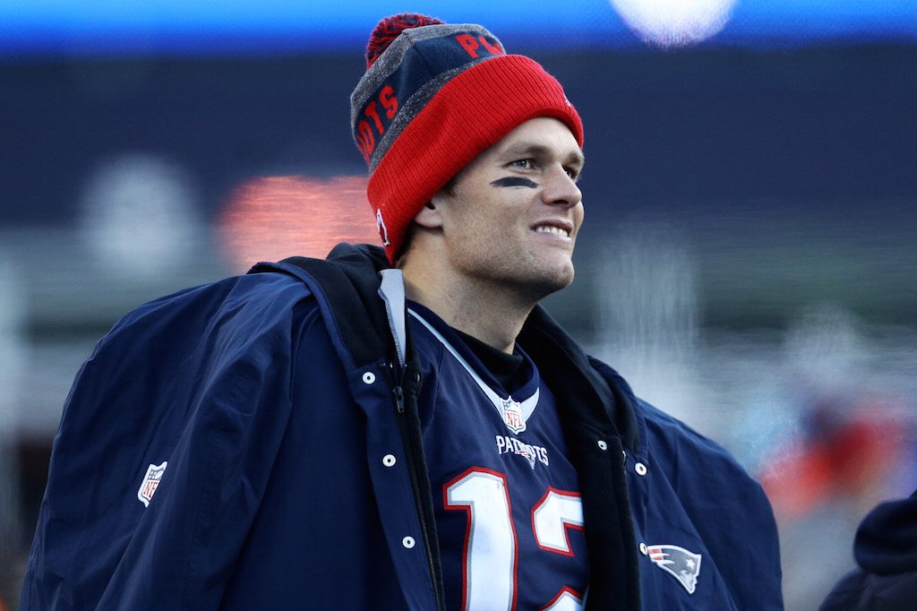 Tom Brady smiles as he sits on the bench.