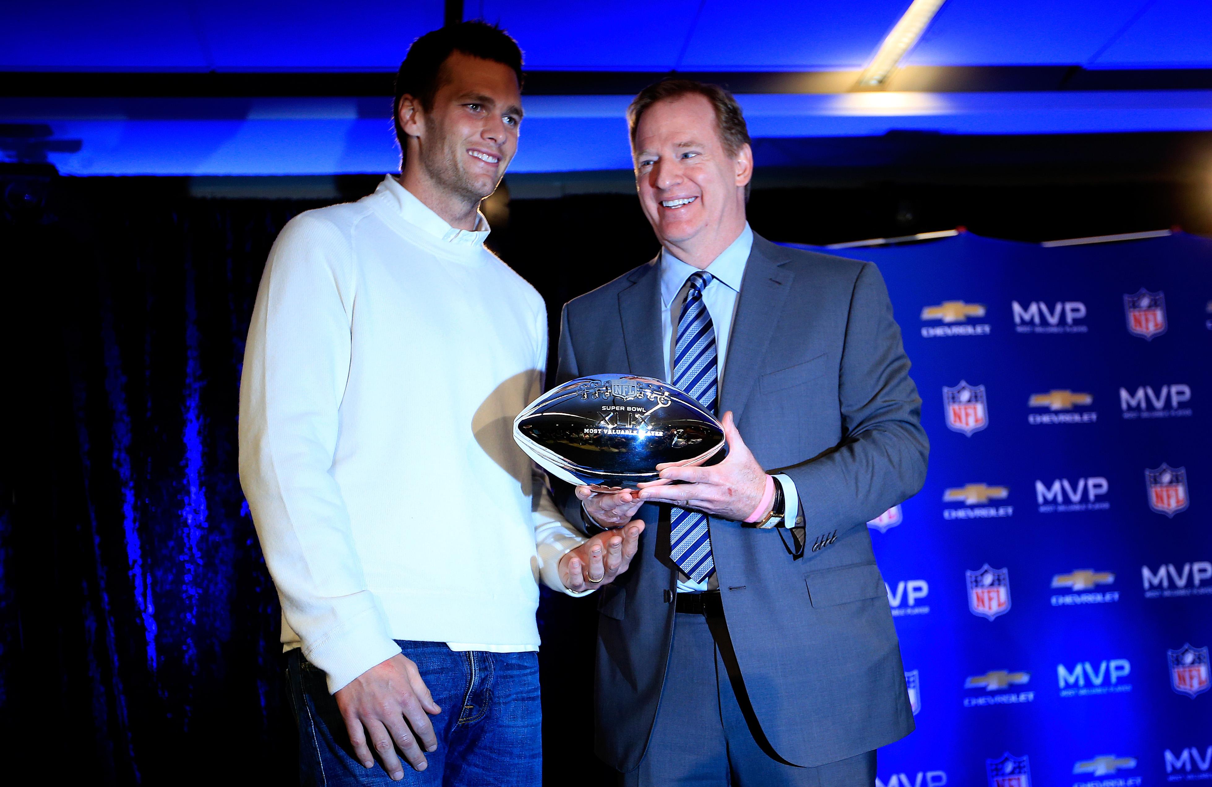 Tom Brady and Roger Goodell stand together on stage.