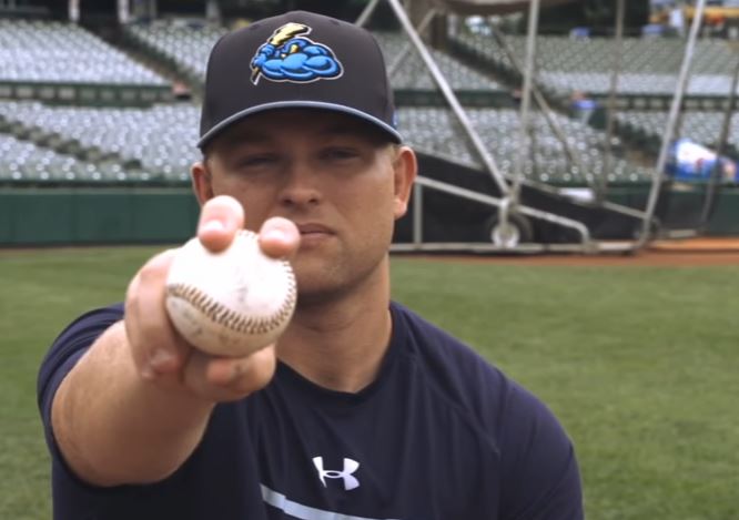 Chance Adams holds up a baseball up towards the camera