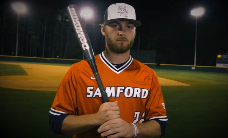 Heath Quinn poses with a bat in front of the field