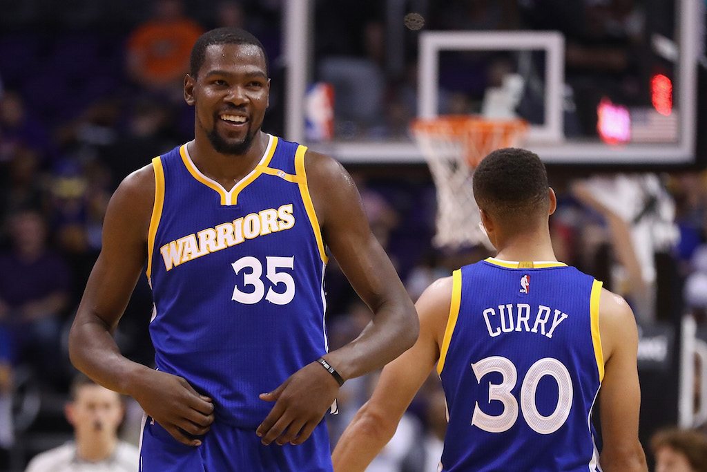 Kevin Durant and Stephen Curry laugh together and celebrate a play.