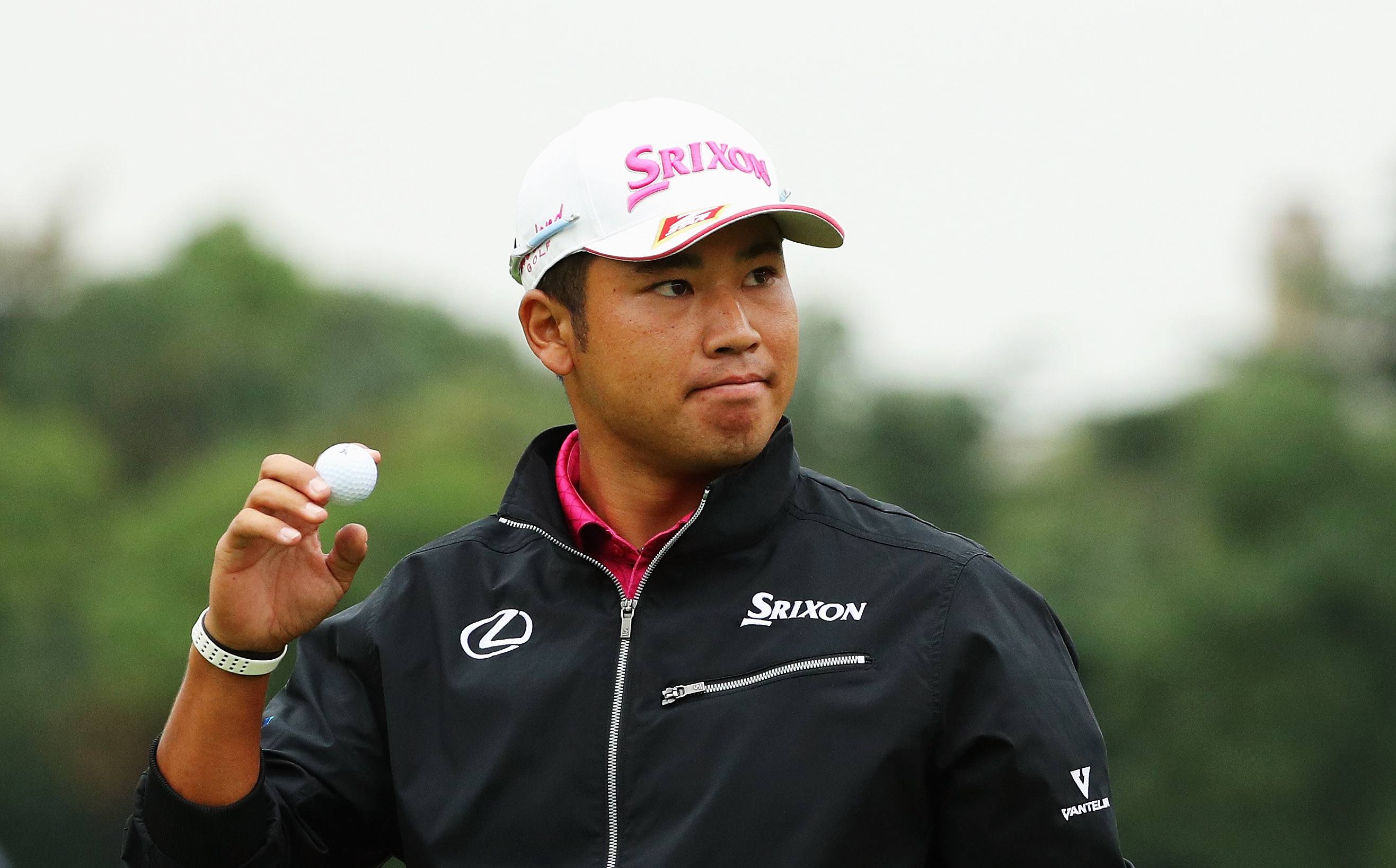 Hideki Matsuyama looks determined as he holds up a golf ball.