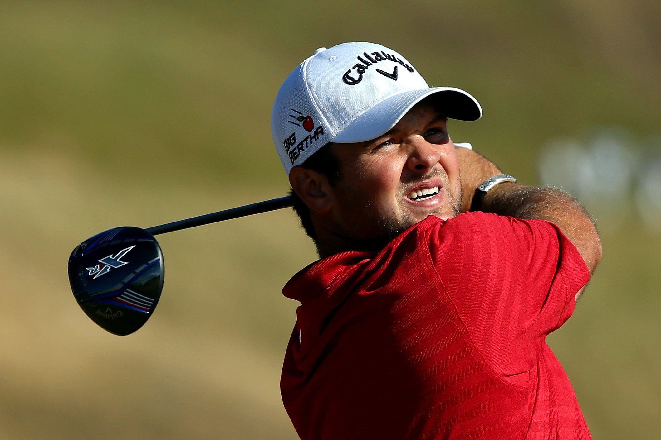 Patrick Reed squints into the sun as he swings.