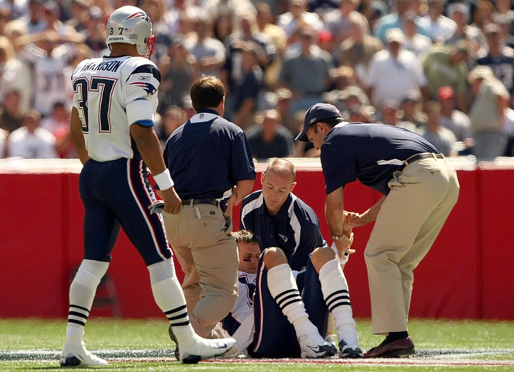 Tom Brady stands up with the aid of the Patriots staff after tearing his ACL against the Kansas City Chiefs.