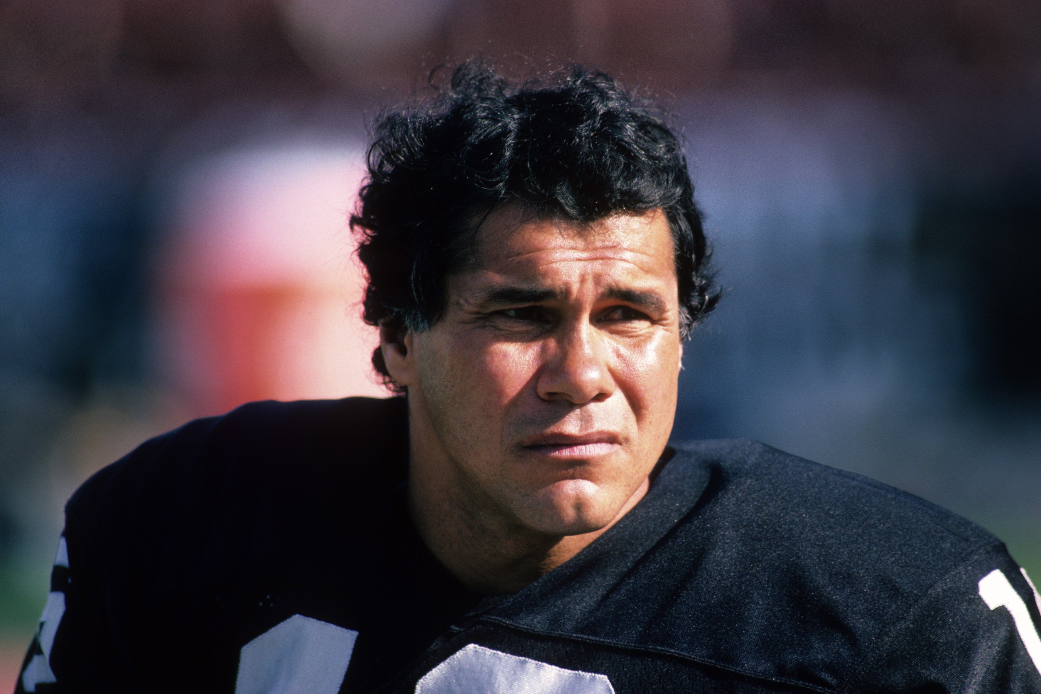 Jim Plunkett sits on the field.