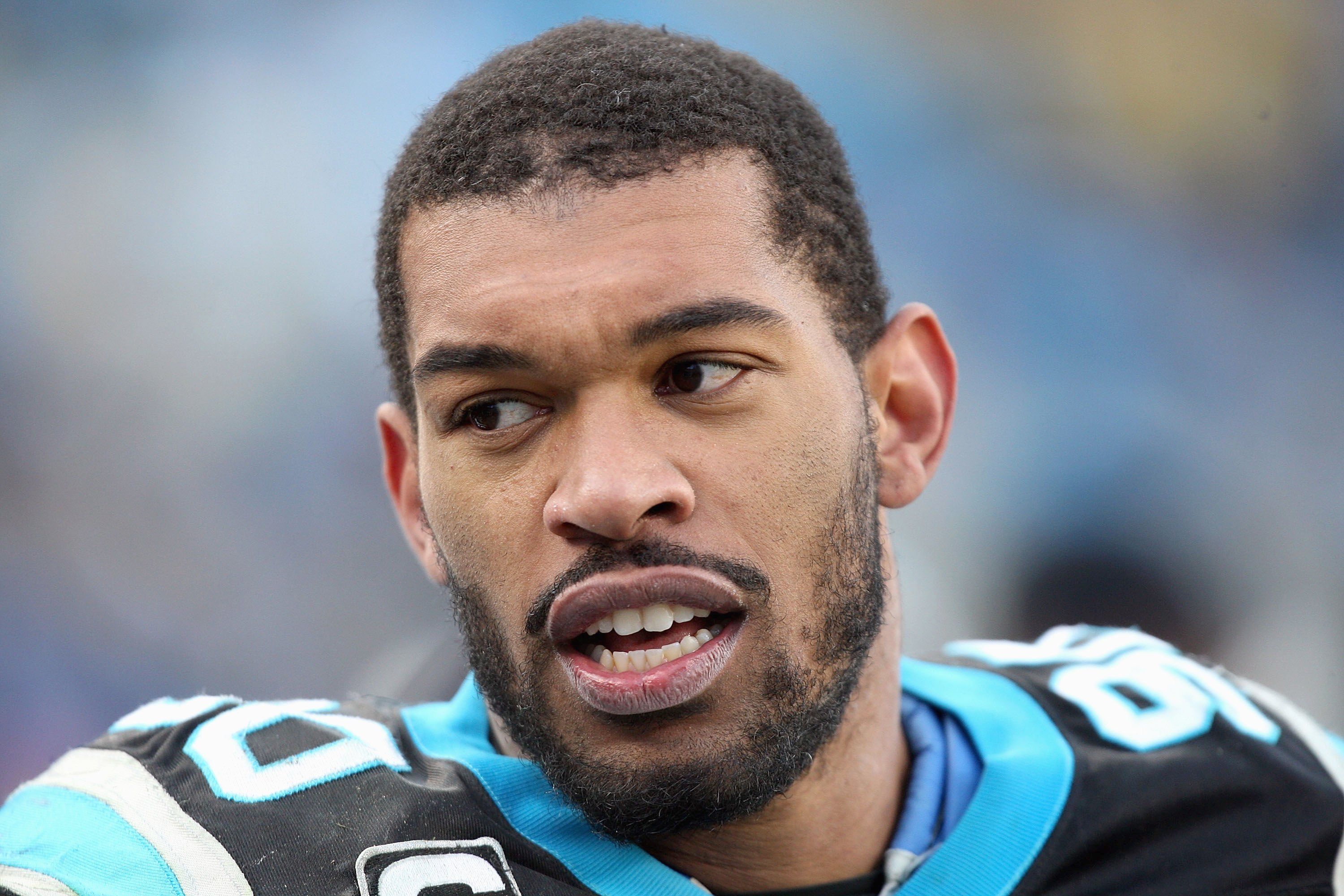 Julius Peppers sits on the sidelines and talks to teammates.