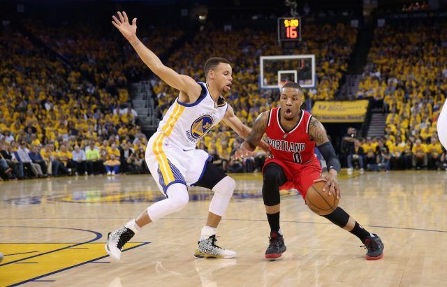 Damian Lillard (R) drives on Stephen Curry.