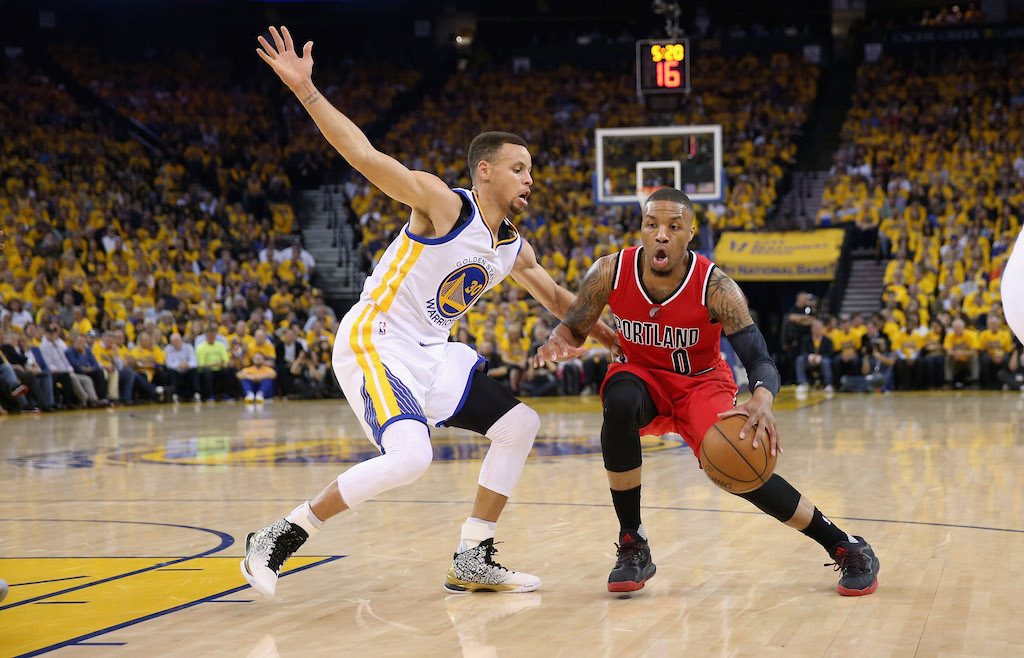 Damian Lillard (R) drives on Stephen Curry.
