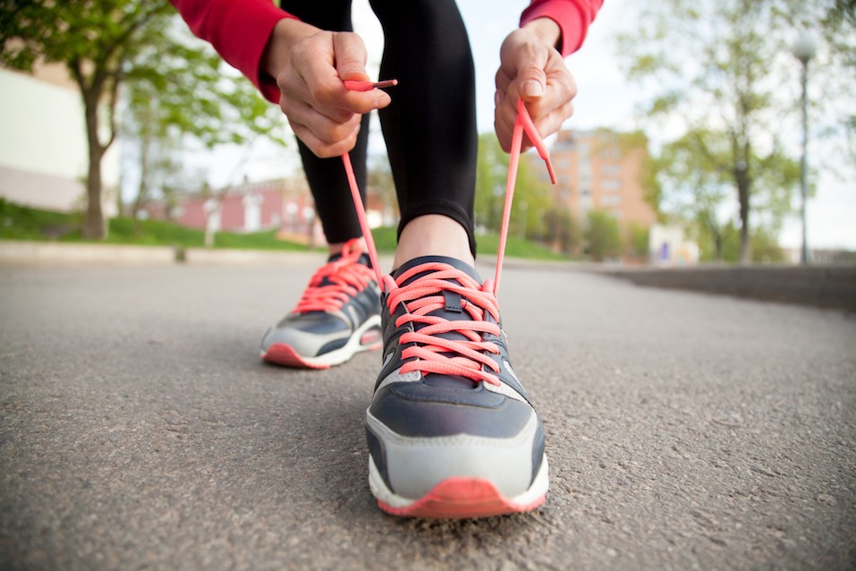 Woman tying shoelaces on running shoes. Female hands lacing running shoes. Closeup