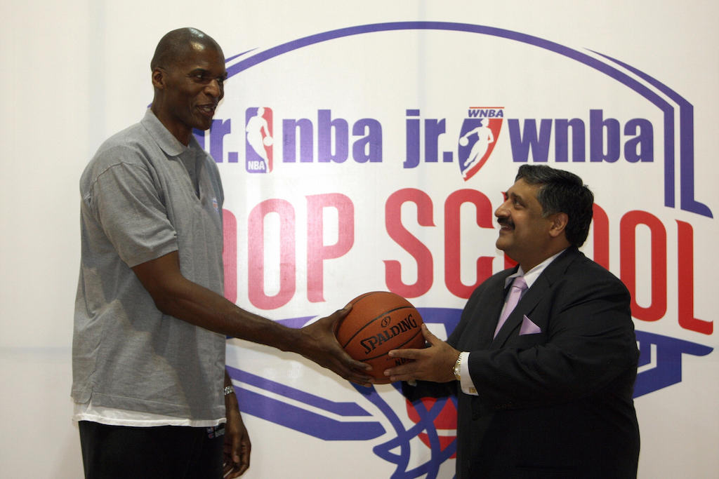 Robert Parish presents a basketball during a press conference.