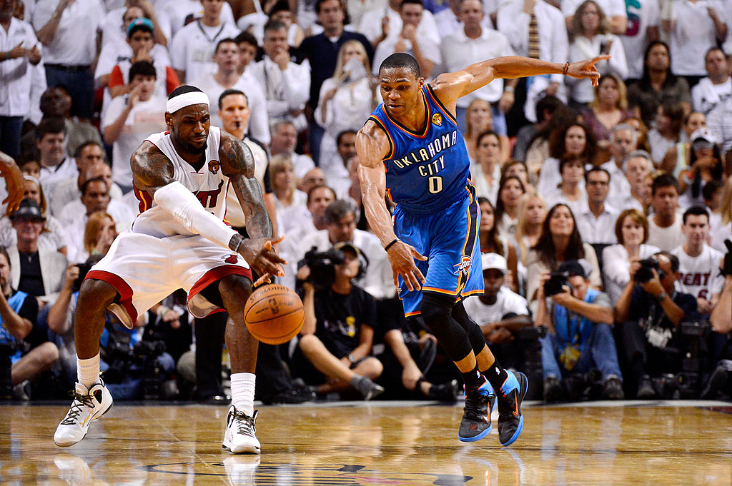 LeBron James grabs the ball in front of Russell Westbrook.