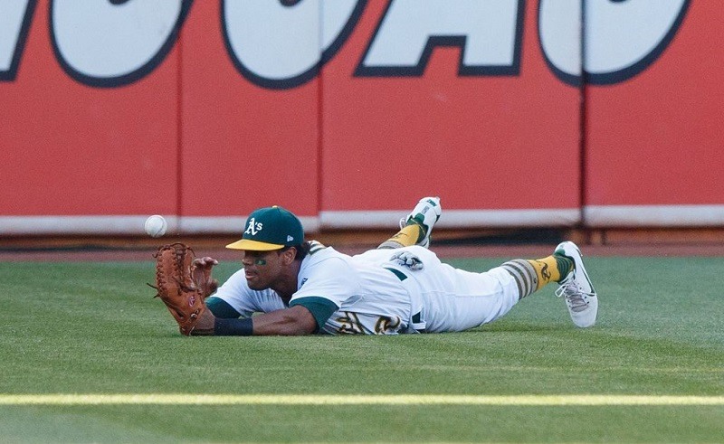 Khris Davis of the Oakland Athletics dives for but is unable to catch a fly ball.
