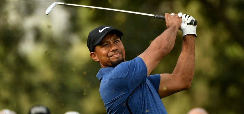 Tiger Woods swings as he is playing golf on the golf course.