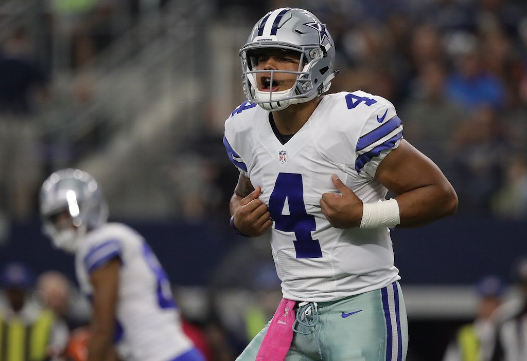 Dak Prescott calls the play. Dak Prescott signals a teammate.