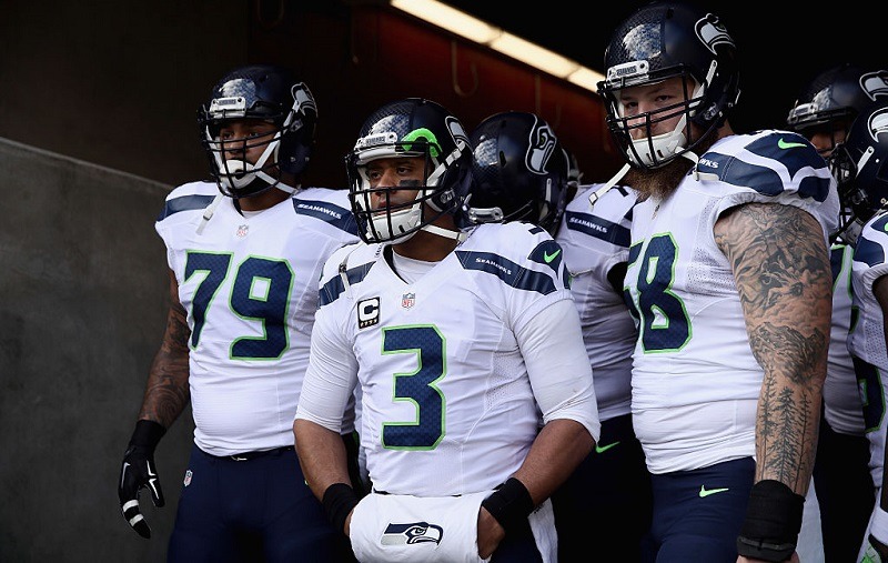 Garry Gilliam, Russell Wilson, and Michael Britt stand together before entering the stadium.