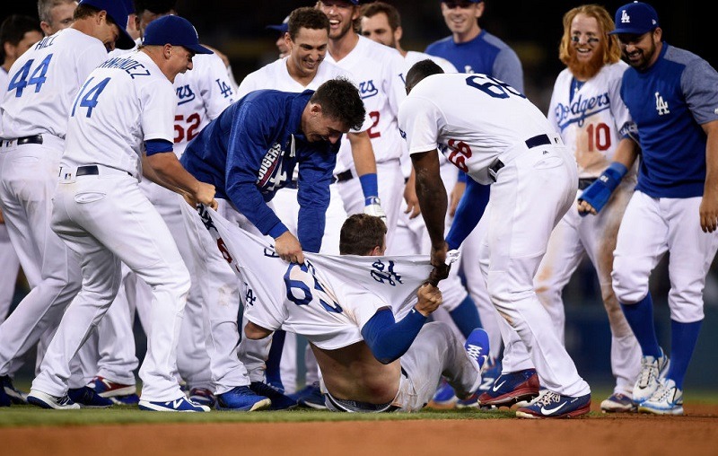 Kyle Farmer #65 of the Los Angeles Dodgers has his shirt ripped apart by teammates.