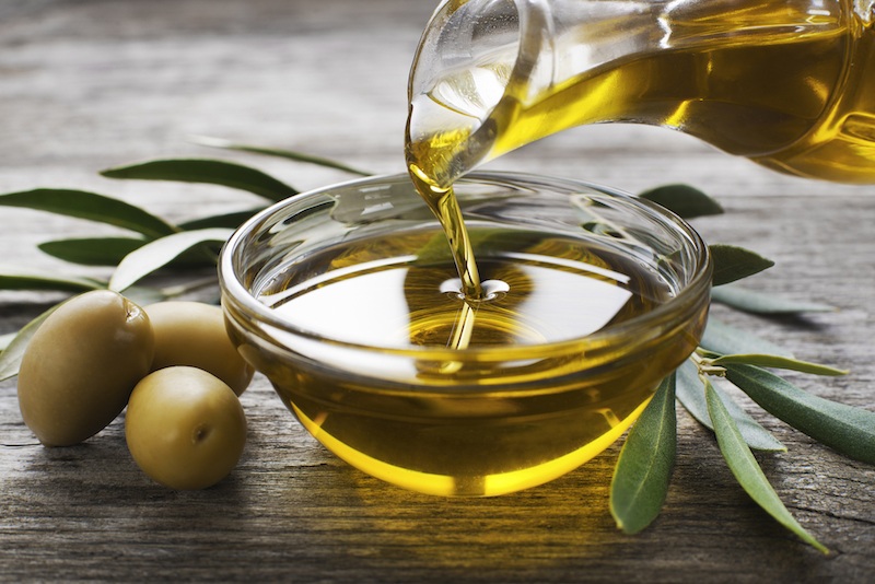 Olive oil in a bowl on a wooden table. Olive oil in a bowl on a wooden table.