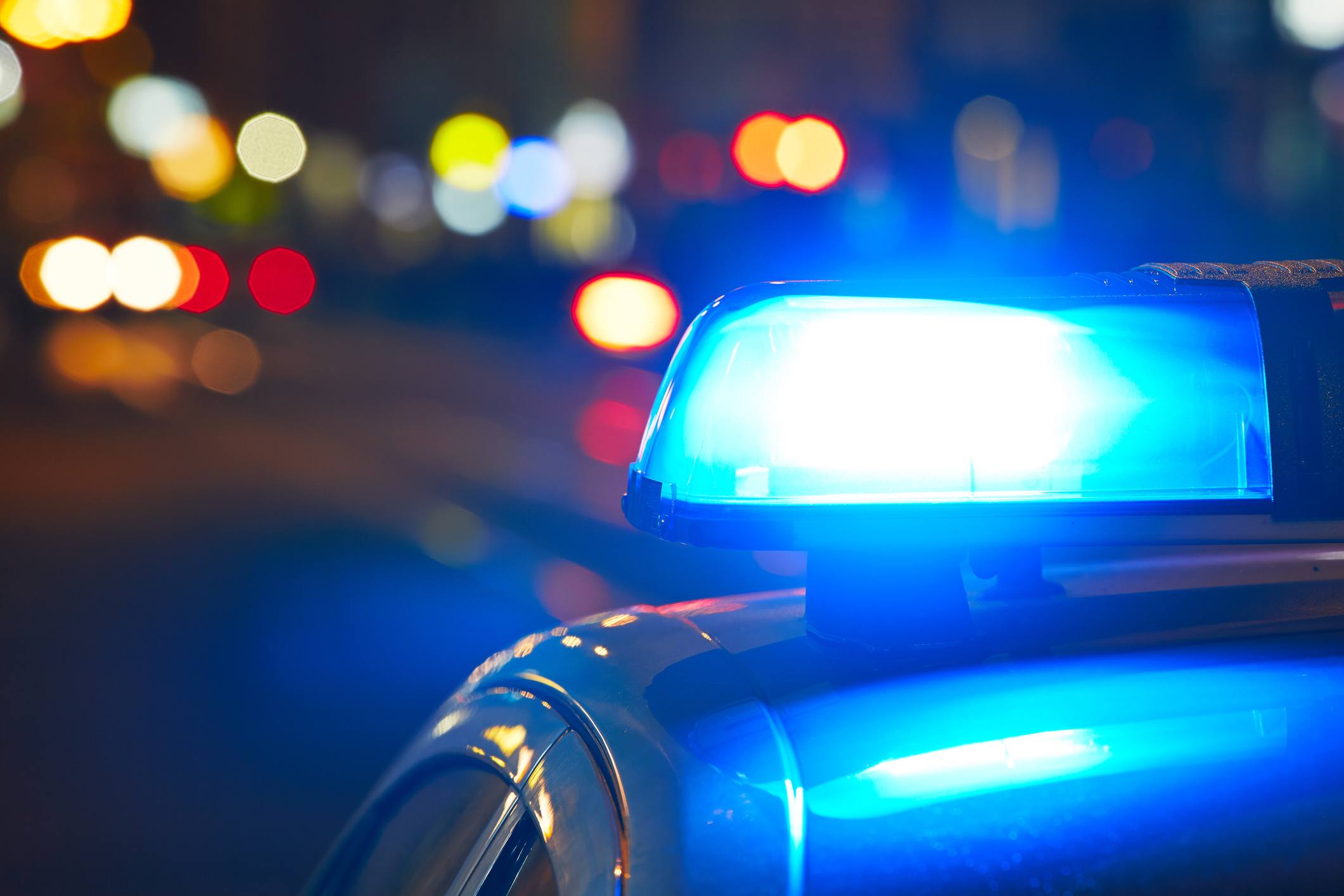 Blue police light on top of a police car at night.