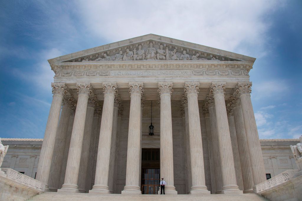 A police officer stands guard on the steps of the US Supreme Court in Washington, DC on a partly cloudy day