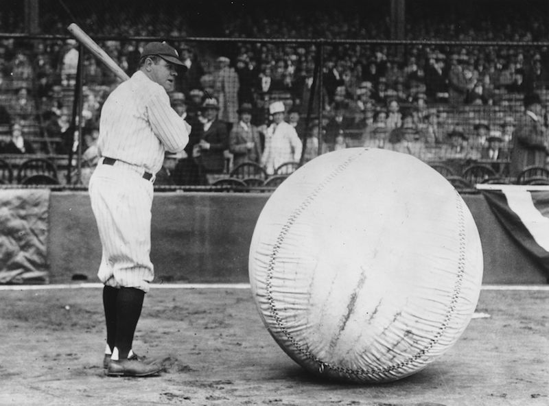 Babe Ruth swinging at a large ball. 