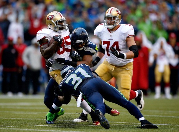 Vernon Davis #85 of the San Francisco 49ers gets tackled by Mike Morgan #57 and Kam Chancellor #31 of the Seattle Seahawks 