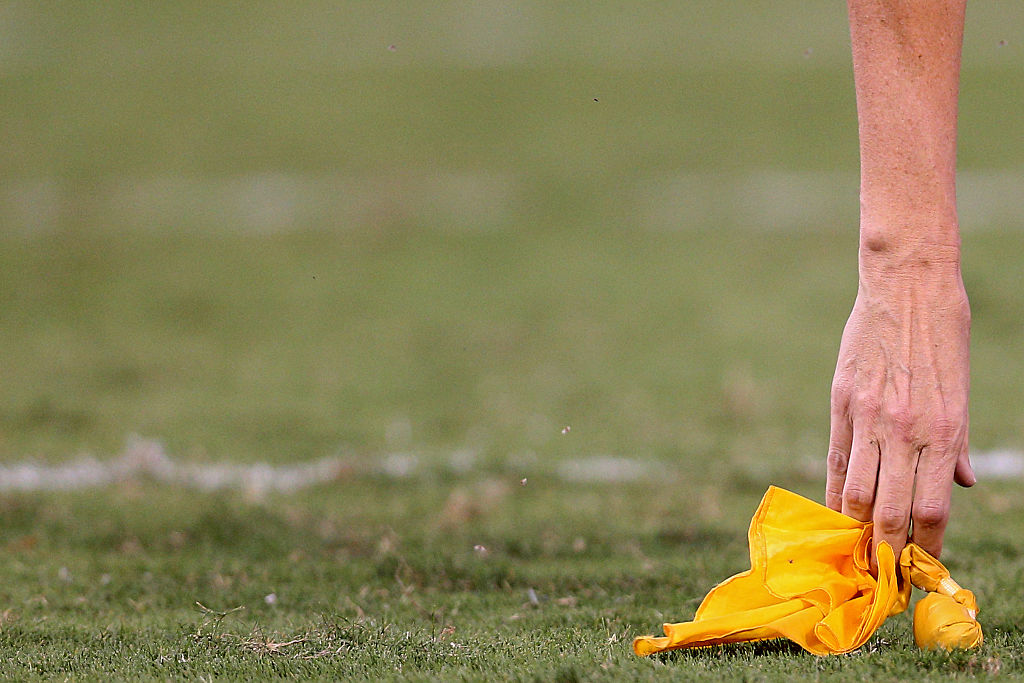 A referee picks up a penalty flag 