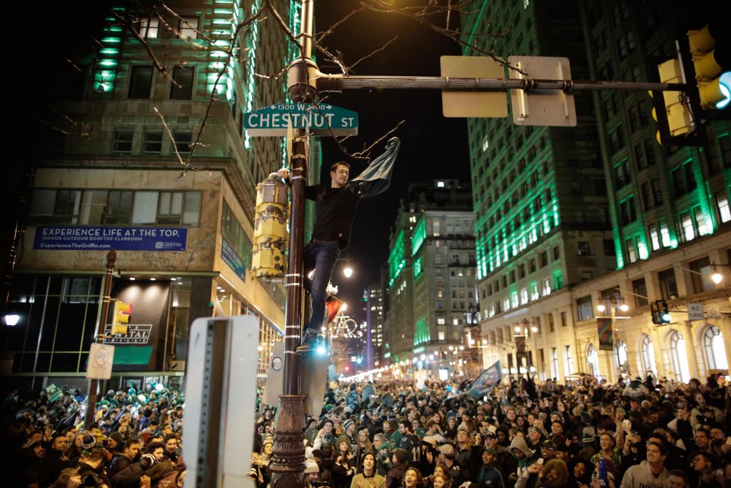 A man climbs a traffic pole as Philadelphia Eagles fans celebrate