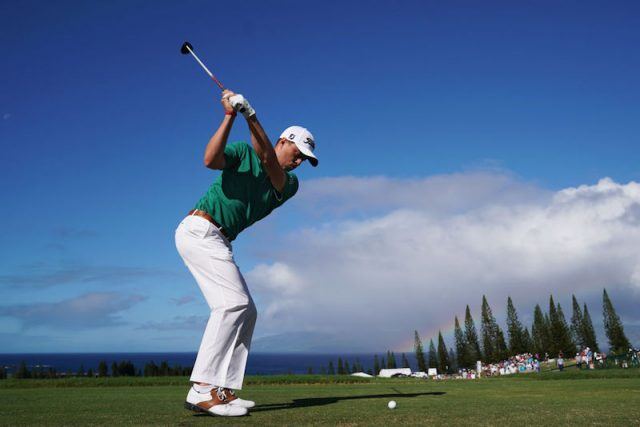 Justin Thomas swinging a club as he aims for the golf ball. Justin Thomas swinging a club as he aims for the golf ball.