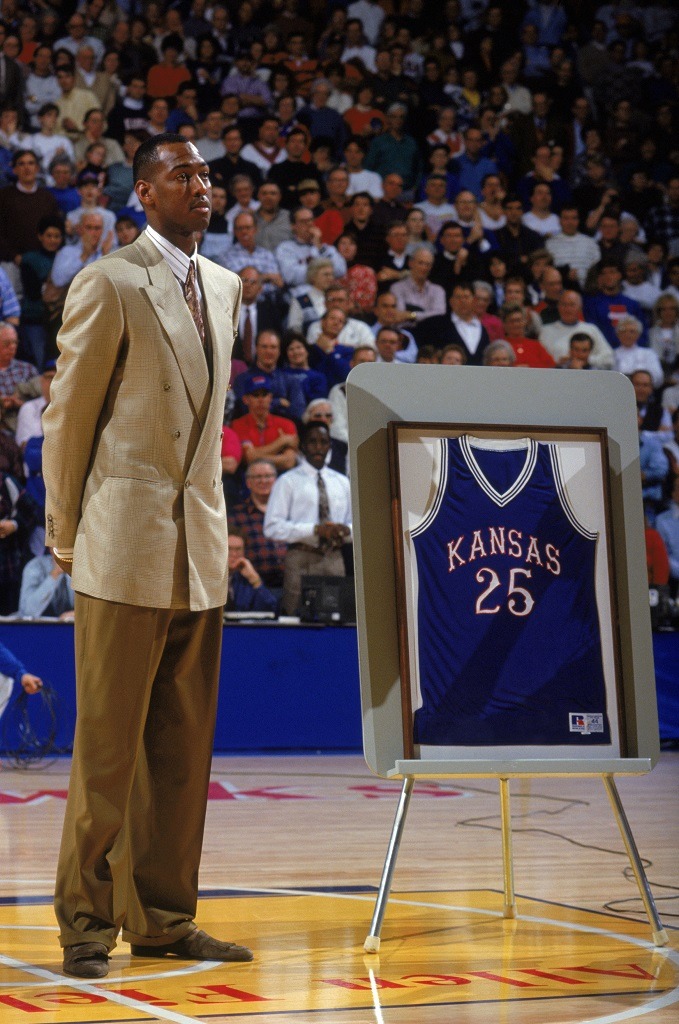 Former University of Kansas Jayhawk Danny Manning stands in center court next to his framed #25 Jayhawk jersey during a Kansas game.