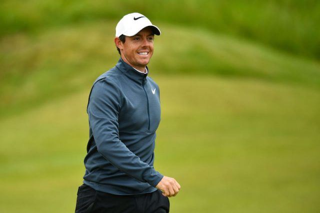 Rory McIlroy smiles while standing on the golf course. Rory McIlroy smiles while standing on the golf course.