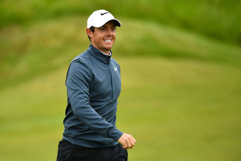 Rory McIlroy smiles while standing on the golf course. Rory McIlroy smiles while standing on the golf course.