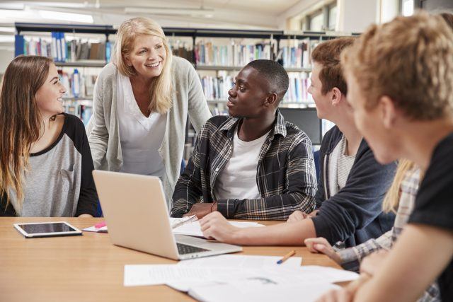 Female Teacher Working With College Students In Library Female Teacher Working With College Students In Library