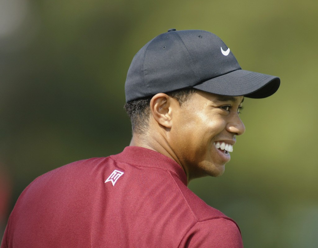 Tiger Woods smiling while on the golf course.