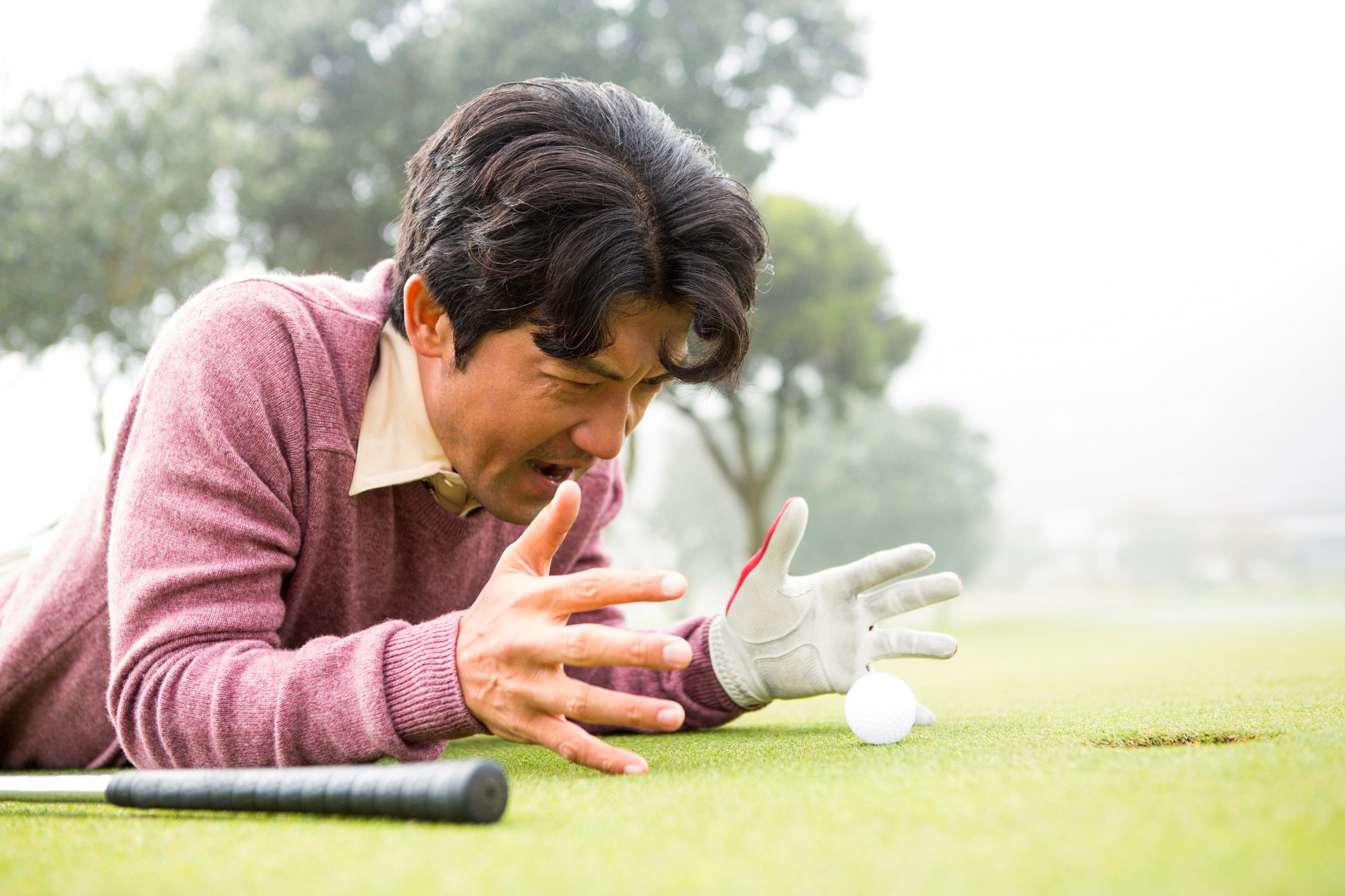 angry Golfer lying near golf ball