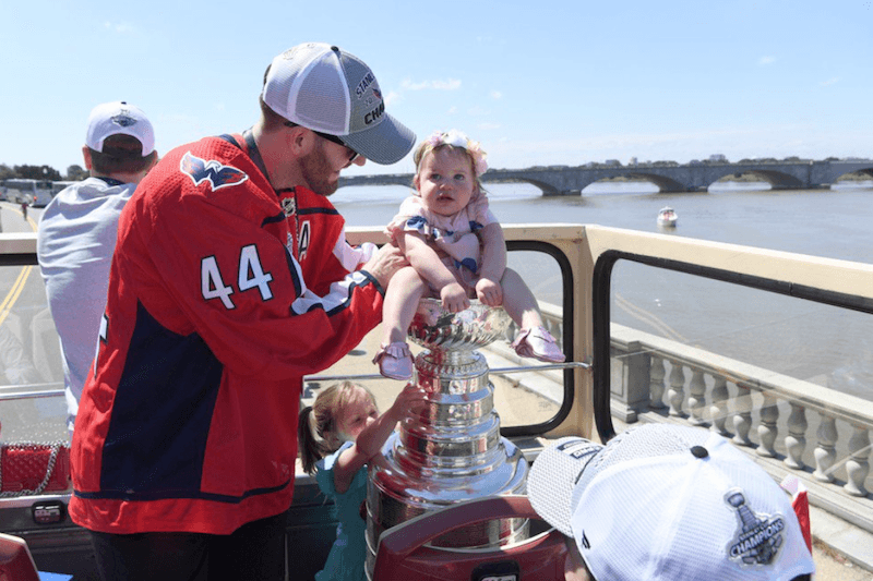 An athlete holding the baby over the cup. An athlete holding the baby over the cup.