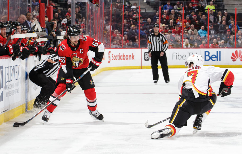 TJ Brodie of the Calgary Flames goes down on a knee to successfully block a pass from Erik Karlsson of the Ottawa Senators.