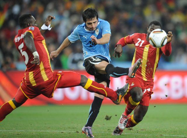 Uruguay's defender Maximiliano Pereira kicks the ball away from Ghana's defender John Mensah (L) and Ghana's midfielder Kwadwo Asamoah during the 2010 World Cup quarter-final match
