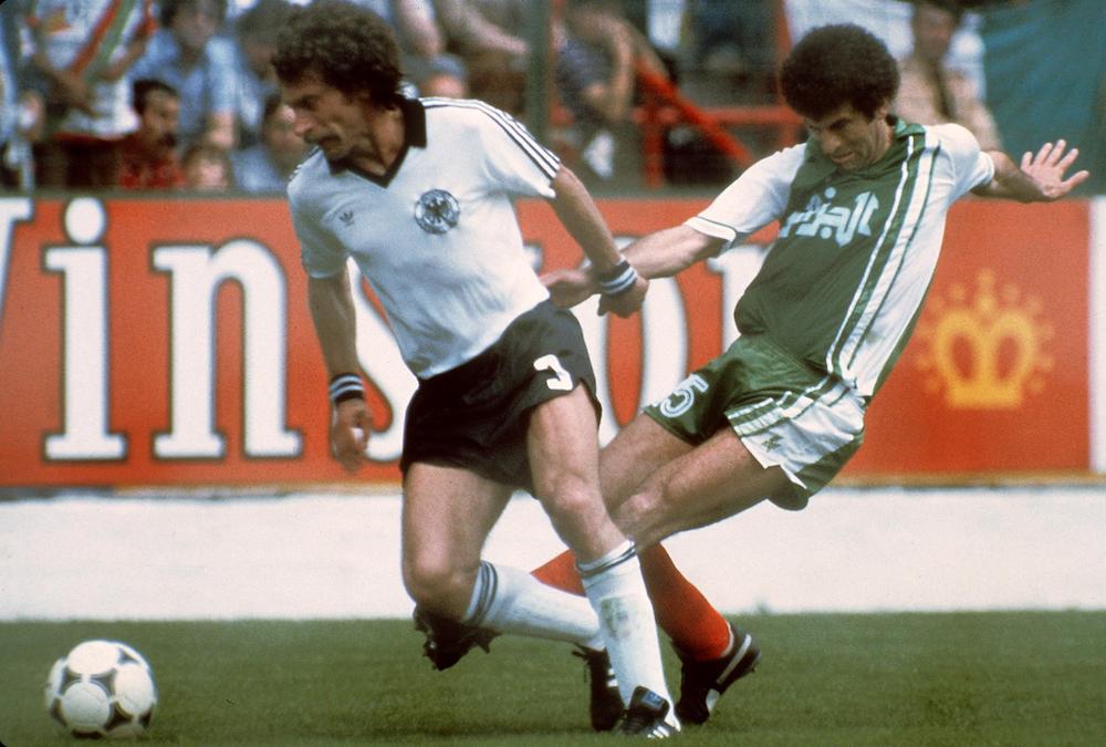 West German defender Paul Breitner (R) tries to control the ball under pressure from Algerian midfiedler Mustapha Dahleb duringthe 1982 World Cup