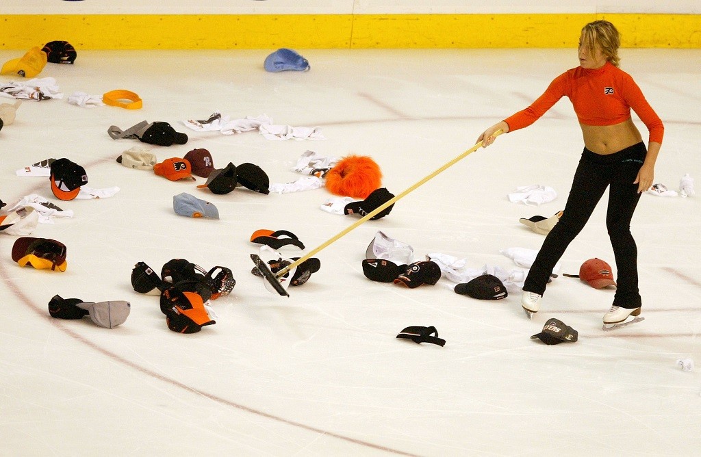An ice crew member cleans the headgear off the ice An ice crew member cleans the headgear off the ice