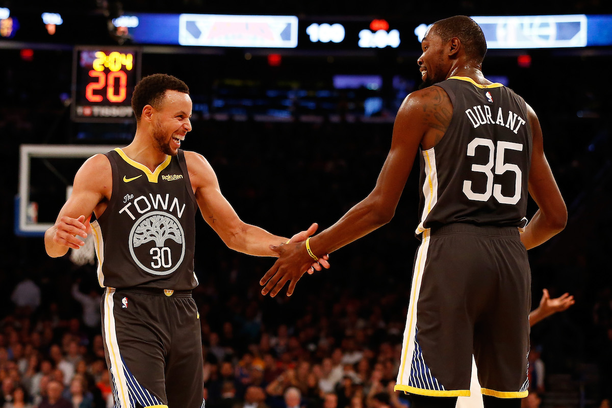 Stephen Curry and Kevin Durant high-five while teammates on the Kevin Durant