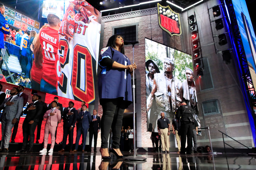 Players (background) stand for the national anthem before the first round of the 2019 NFL draft.