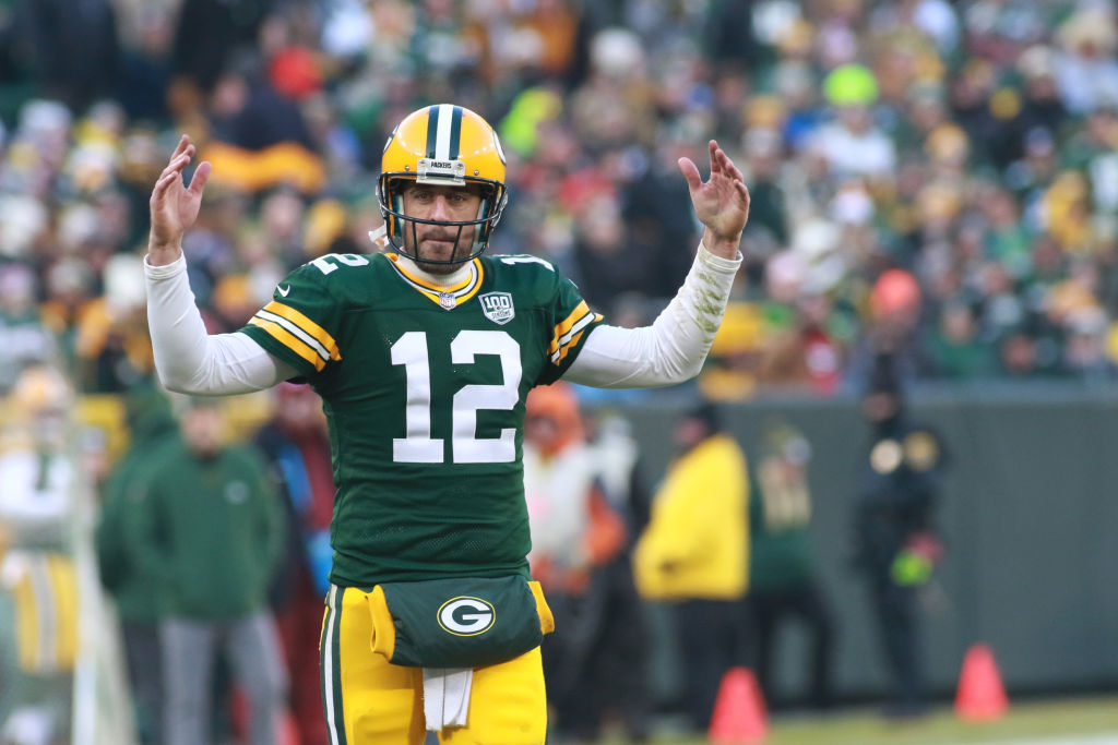 Aaron Rodgers lifts arms up on the field at Lambeau