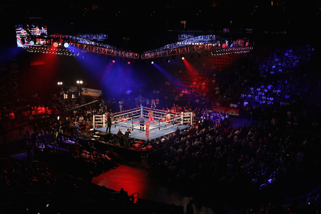 A packed arena with a boxing ring set up in the middle
