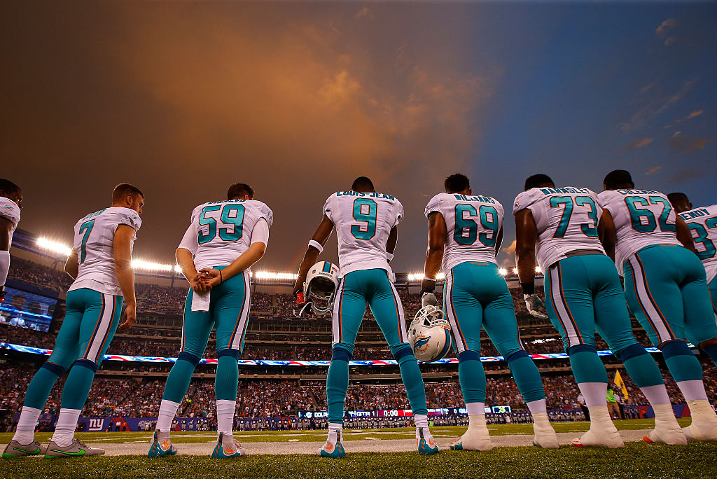 Miami Dolphins' players wearing their away jerseys on the sidelines.