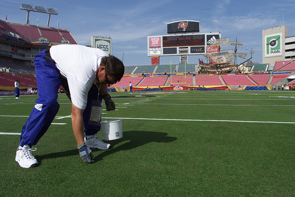 An NFL groundskeeper painting the field before a game.