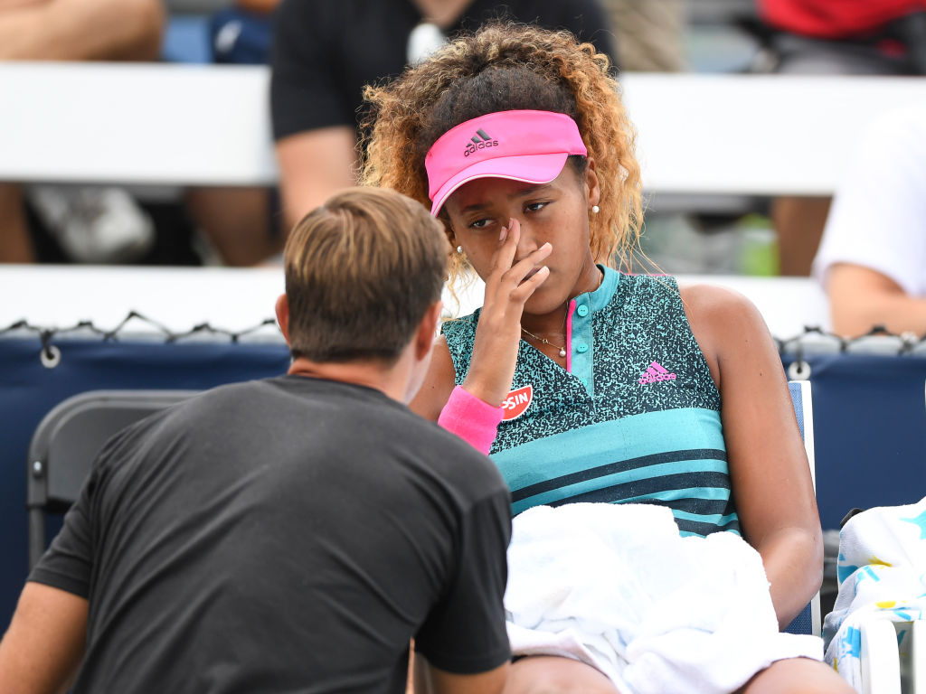 A professional tennis coach talks to Naomi Osaka on the bench.