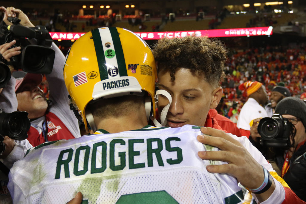 Quarterbacks Aaron Rodgers and Patrick Mahomes embrace at midfield after a game.