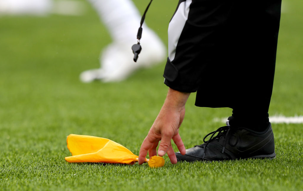 An NFL referee picking up a penalty flag